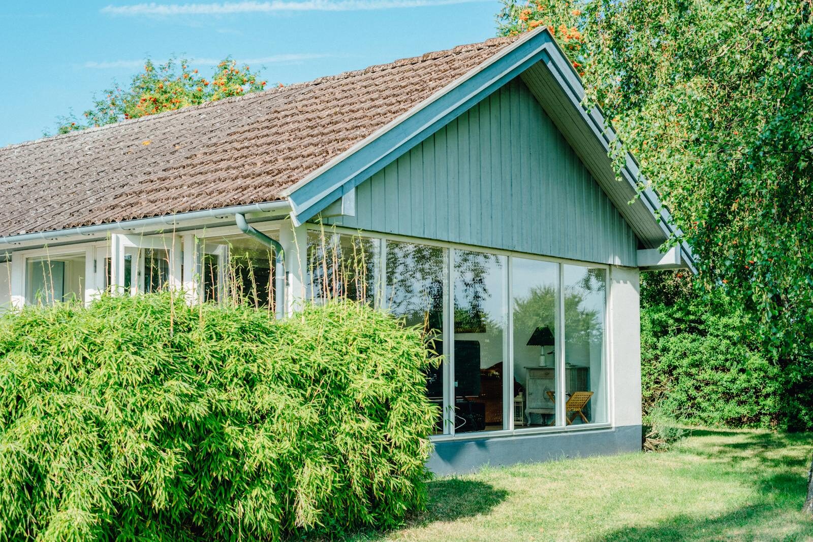 Bright and airy modern cabin with large glass panels surrounded by lush greenery.